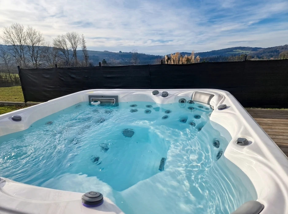 Jacuzzi extérieur haut de gamme installé sur une terrasse en bois composite, avec vue panoramique sur collines boisées