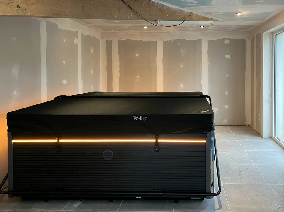 Spa Wellis installé dans une pièce en cours de finition, murs en plaques de plâtre avec joints apparents, sol en carrelage grès cérame