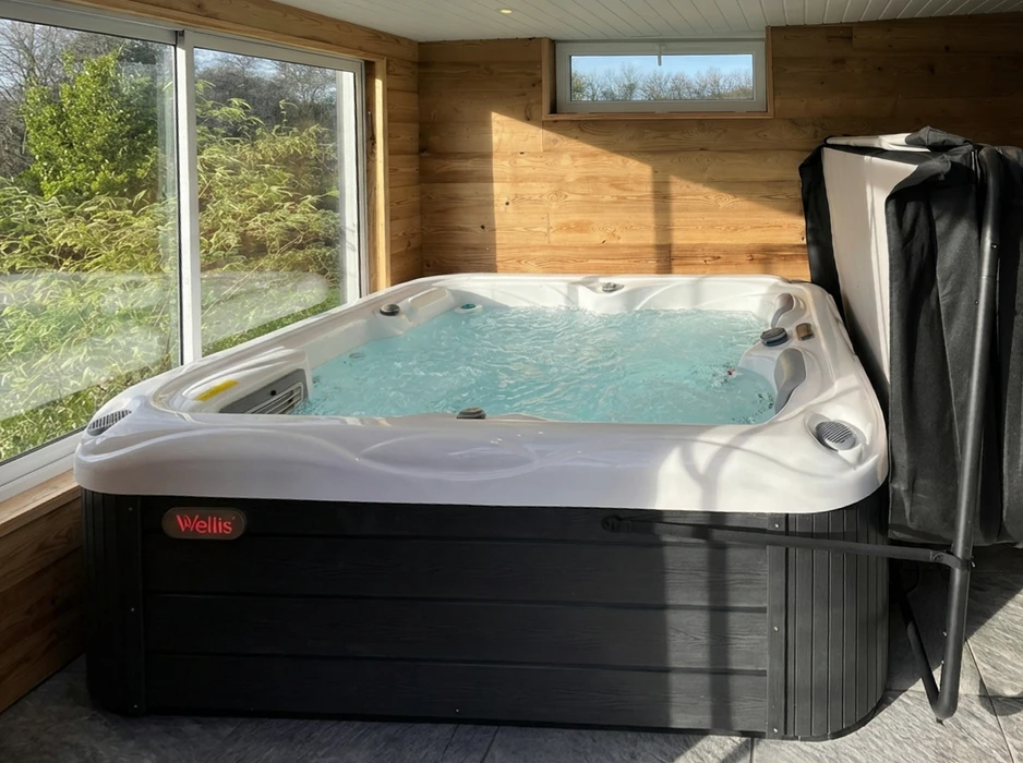 Spa jacuzzi intérieur installé dans un chalet en bois, baie vitrée panoramique avec vue sur végétation