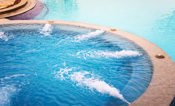 Espace aquatique extérieur avec jacuzzi circulaire en fonctionnement, jets d'hydromassage actifs créant des remous et écume blanche