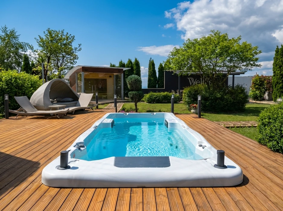 Terrasse en bois exotique avec spa de nage autoportant blanc, coque acrylique, jets de massage intégrés, éclairages LED périphériques