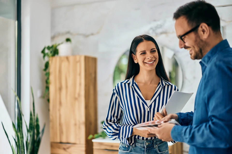 Réunion de travail en intérieur avec trois professionnels analysant des plans techniques sur une table en bois
