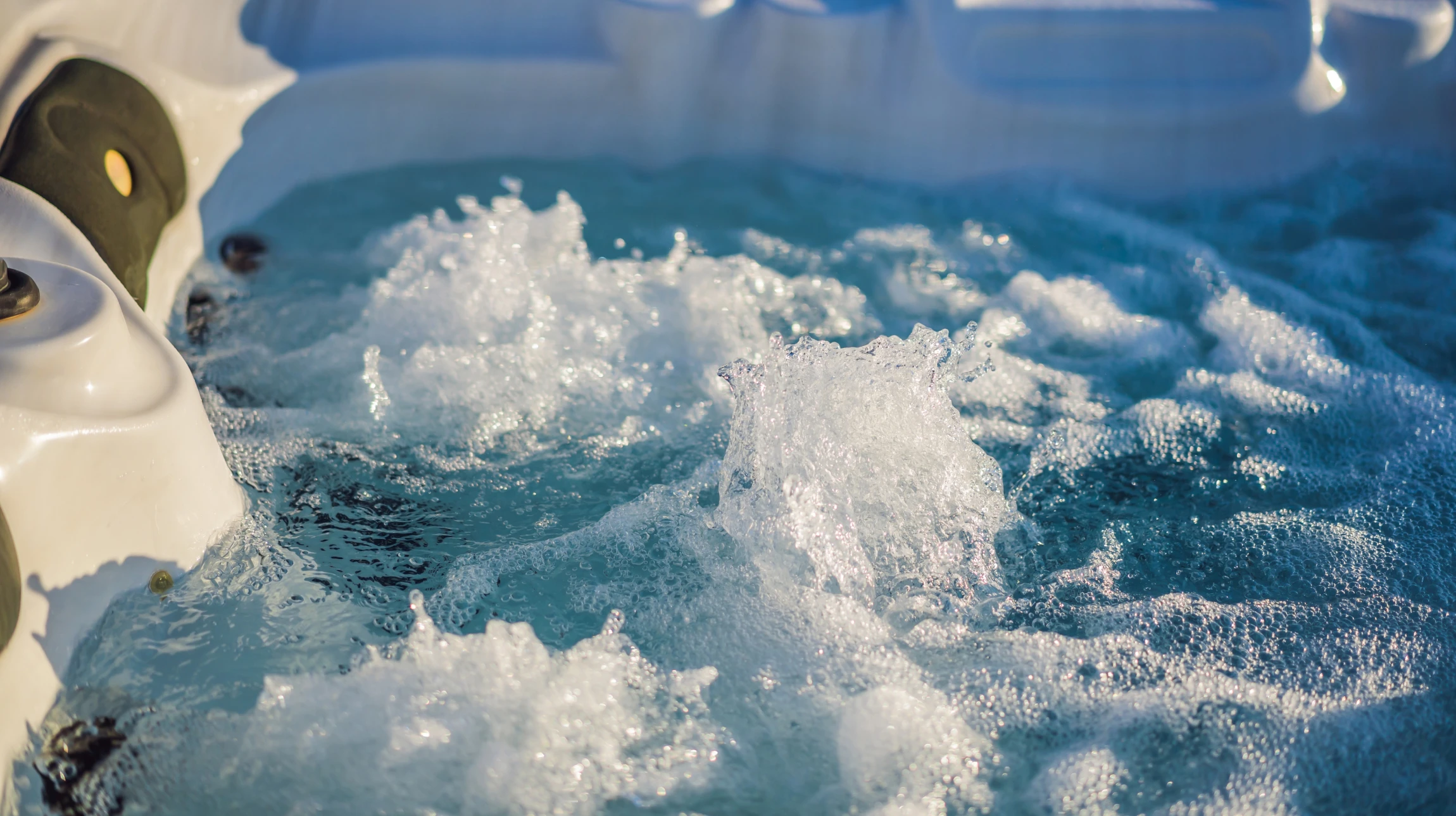 Scène extérieure montrant un spa ou jacuzzi en fonctionnement avec cascade d'eau, entouré de végétation fleurie rose et mobilier moderne gris