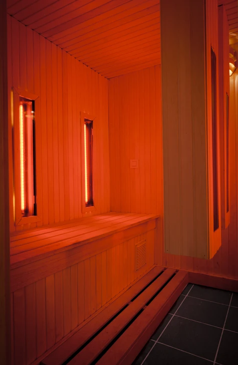 Intérieur moderne d'un showroom de bien-être aquatique. Vue d'exposition montrant plusieurs modèles de saunas infrarouges en bois, spas et équipements de relaxation disposés de manière professionnelle. Espace lumineux et bien organisé avec carrelage ou sol époxy, éclairage professionnel mettant en valeur les produits, permettant aux clients de comparer les différentes gammes côte à côte dans un contexte de showroom commercial. Aucun client ou personne visible, accent sur la présentation claire et accessible des modèles d'exposition.